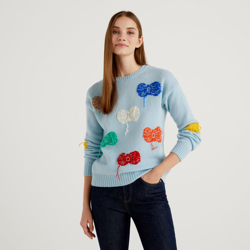 Light blue virgin wool sweater with balls of yarn